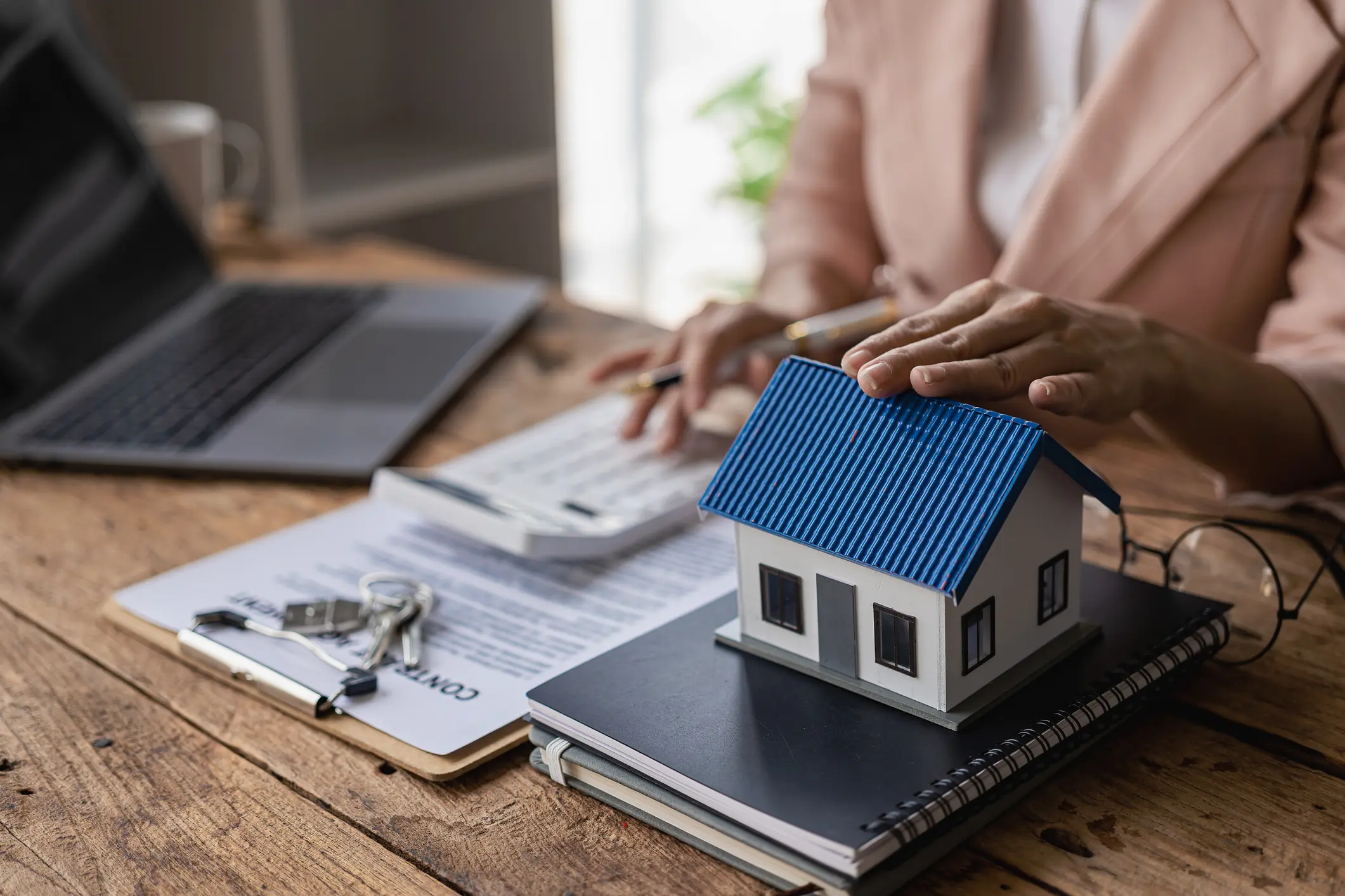 Model house on desk with documents.