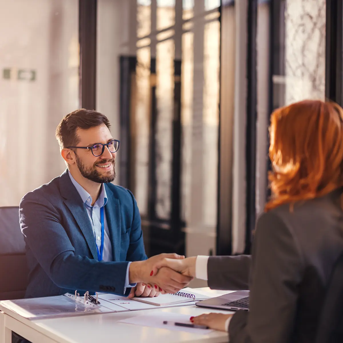 Business meeting handshake in a bright office.